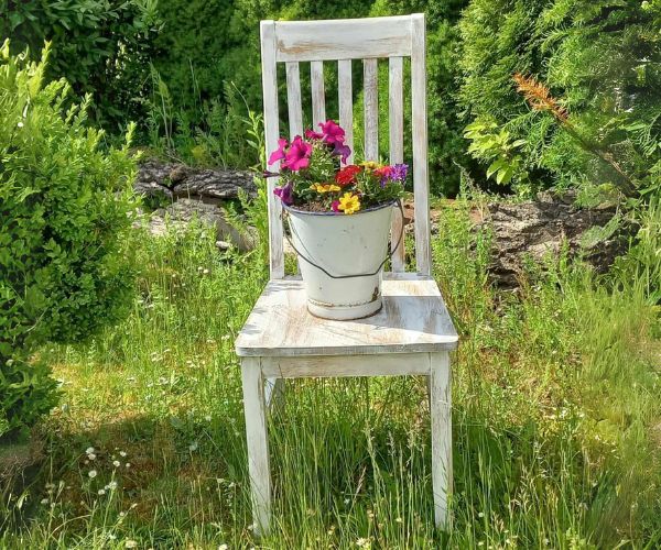weisser Stuhl mit Blumenkuebel